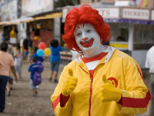 a mcdonald 's clown is giving a thumbs up in front of a ticket booth