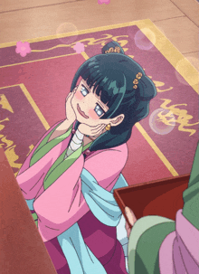 a girl in a pink and green kimono is sitting on the floor