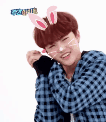 a boy wearing bunny ears and a plaid shirt is smiling