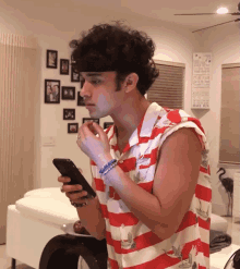 a man in a red and white striped shirt is looking at his cell phone