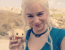 a woman is holding a funko pop of a woman in a blue dress .