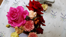 a bunch of flowers on a table with a teapot in the background