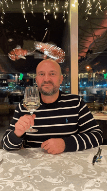 a man sitting at a table with a glass of wine in his hand