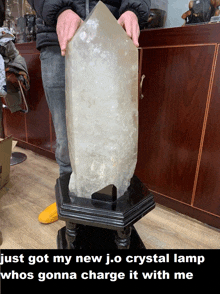 a man is holding a large crystal in front of a wooden counter