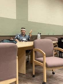 a man wearing a white headband sits at a desk with a dell laptop