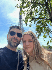 a man and a woman are posing for a picture in front of the eiffel tower