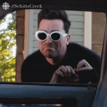 a man wearing sunglasses looks out of a car window