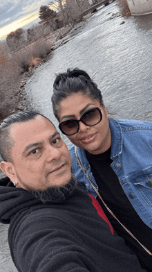 a man and a woman are posing for a picture near a river