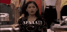 a woman is standing in front of a display of clothes in a store and says apaaa !!! .