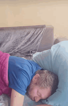 a man in a blue shirt is laying on a bed