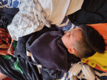 a young boy is laying on a bed with blankets