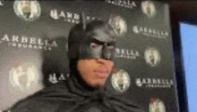 a man is wearing a batman costume and mask .