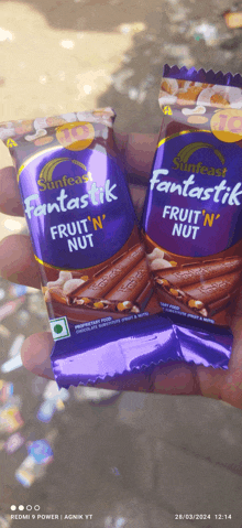 a person is holding two fantastic fruit n nut bars