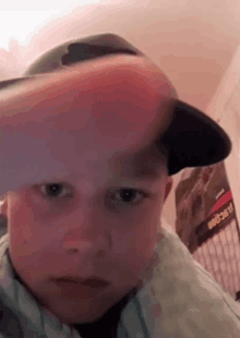 a young boy is wearing a baseball cap and making a funny face .