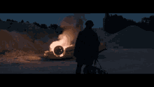 a man standing in front of a burning car with a text message from tiffany at 8:20 pm