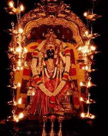 a statue of a goddess is surrounded by candles and garlands