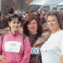 three women are posing for a picture and one has the number 100 on her jacket