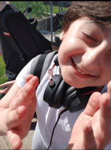 a young boy wearing headphones is smiling and giving a middle finger