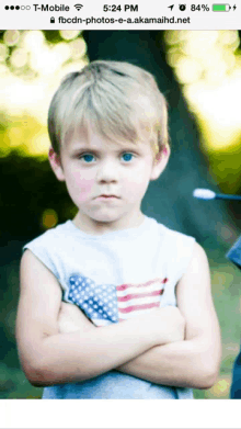 a young boy with his arms crossed is shown on a cell phone screen