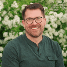 a man with glasses and a green shirt is smiling in front of a sign that says the great canadian baking show