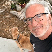 a man wearing glasses is standing next to a dog