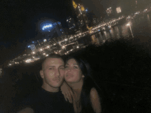 a man and a woman are posing for a picture in front of a city skyline with a sign that says www