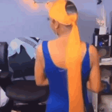 a woman wearing a blue tank top and a yellow headband is standing in a room .