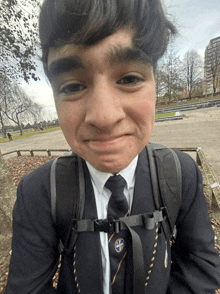 a boy wearing a suit and tie with a cross on his tie