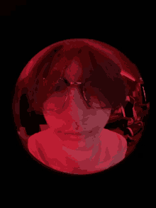 a person wearing glasses and a white shirt is in a red sphere