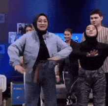 a woman in a hijab is dancing with a group of people in a room .