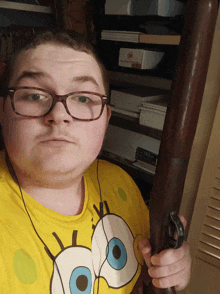 a man wearing a yellow spongebob shirt holds a gun