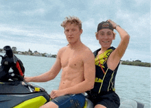 two young men are sitting on a jet ski in the water