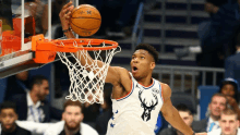 a basketball player with a deer on his jersey dunks a basketball