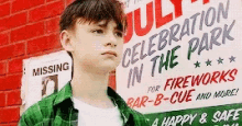 a young boy is standing in front of a sign that says `` july 4th celebration in the park '' .