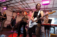 a woman playing a guitar in front of a stage next to a keyboard that says stage