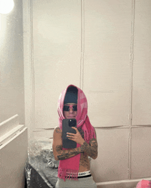 a person wearing a pink scarf taking a picture of themselves