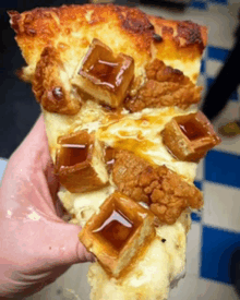 a person is holding a slice of pizza with chicken and waffles on top