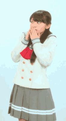 a girl in a school uniform is covering her mouth