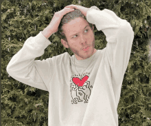 a man wearing a white sweater with a red heart on it