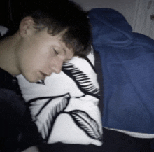 a young man is sleeping on a pillow with a feather design on it