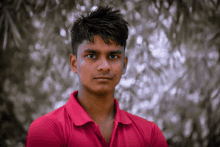 a young man in a red polo shirt looks at the camera