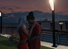 a man and a woman hugging on a pier with a helicopter in the background