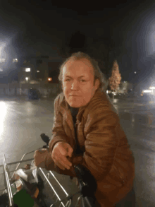 a man in a brown jacket sits in a shopping cart