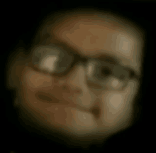 a blurry picture of a person wearing glasses and smiling