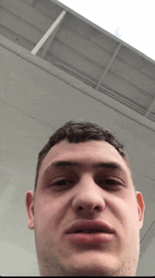 a close up of a man 's face in front of a white ceiling