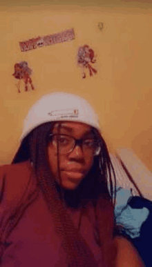 a woman wearing a white hat and glasses is taking a selfie in a bedroom .