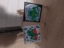 two small paintings of frogs on easels on a table