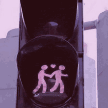 a traffic light with a couple of people holding hands on it