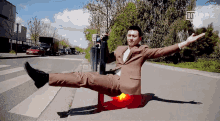 a man in a suit is laying on the ground with his arms outstretched in front of a sign that says no parking