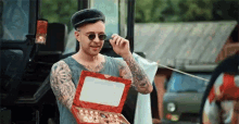 a man with tattoos on his arms is holding a box of chocolates .